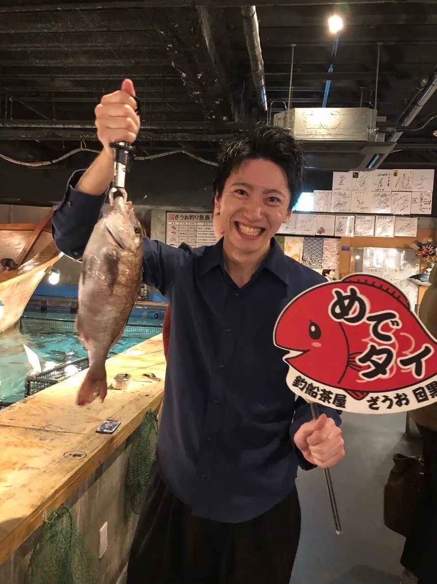 釣り上げた鯛を掲げて笑う皆川卓也さん