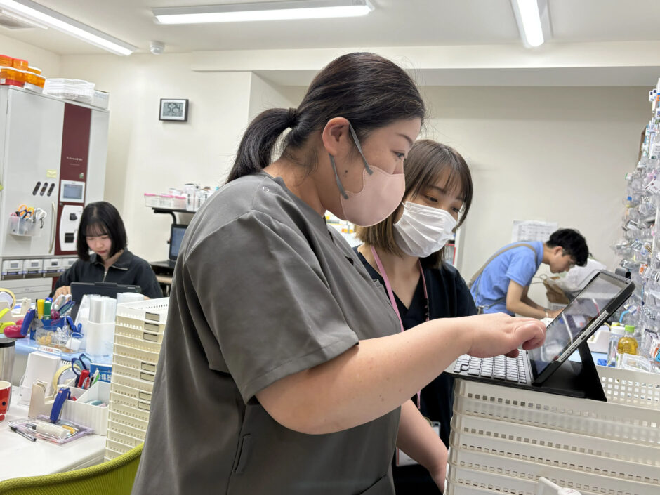 タブレットを見ながらメンバーと確認する森さん｜まんまる薬局 OMF光が丘